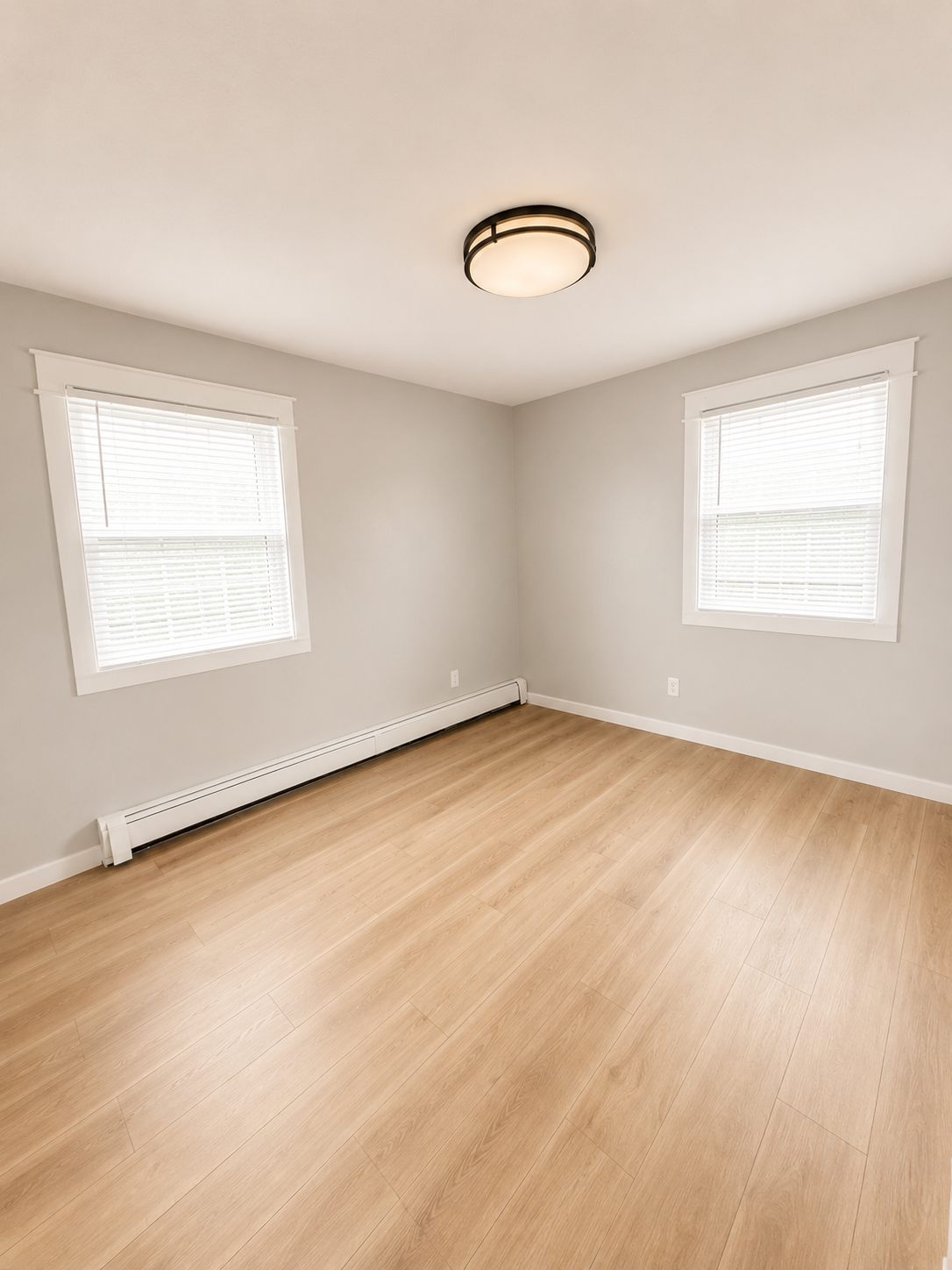 Bedroom with windows on two walls, fresh paint, and new plank flooring