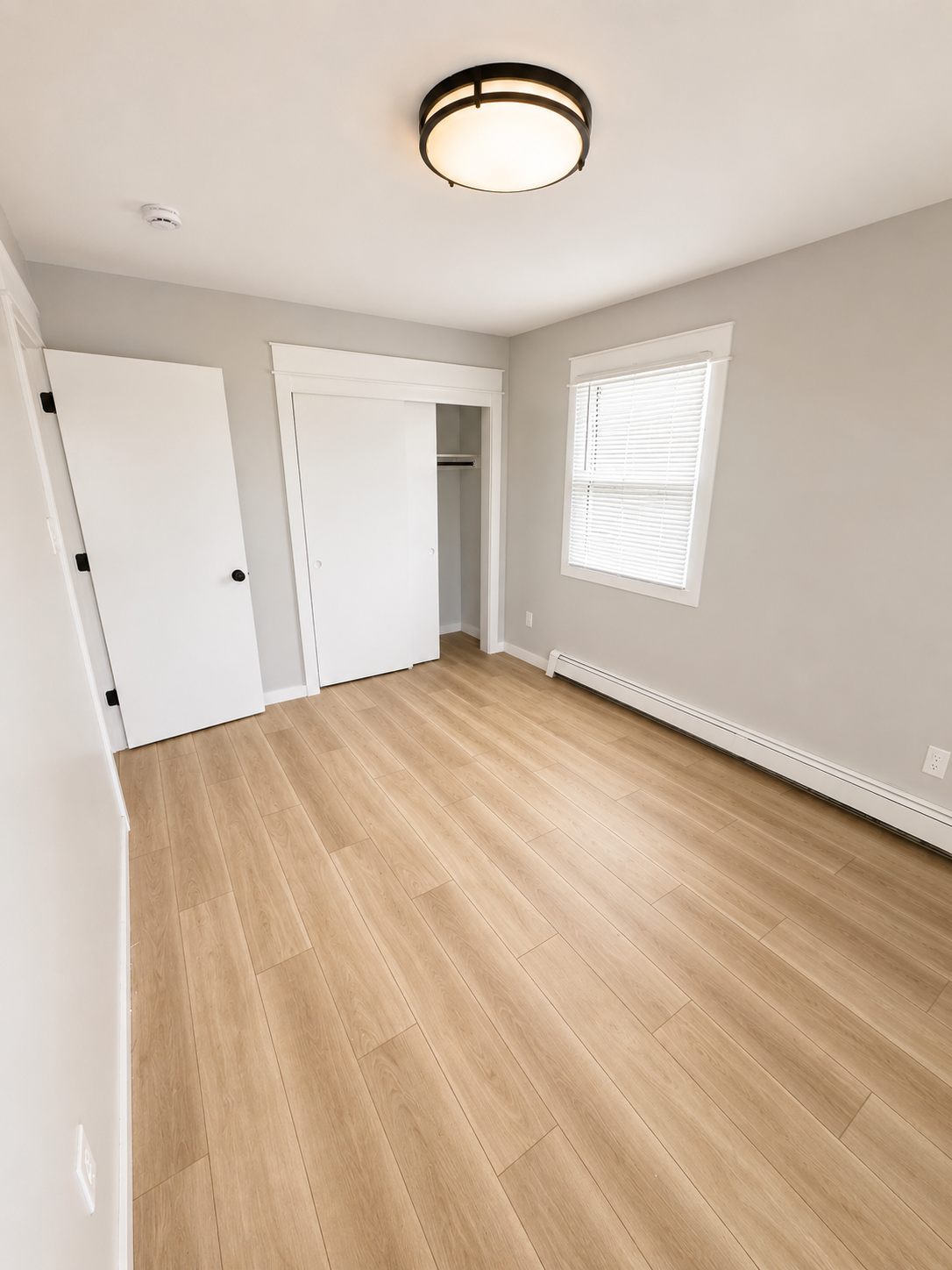 Bedroom with a sliding-door closet and new plank flooring
