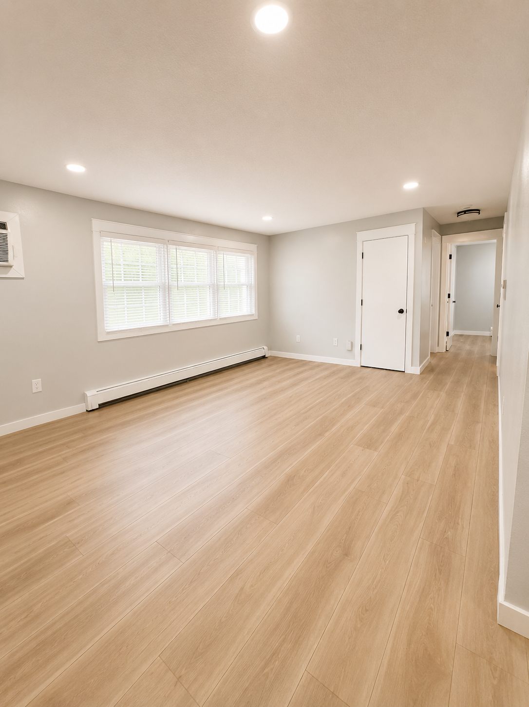 Living room view toward the hallway, with in-unit air conditioning and recessed lighting